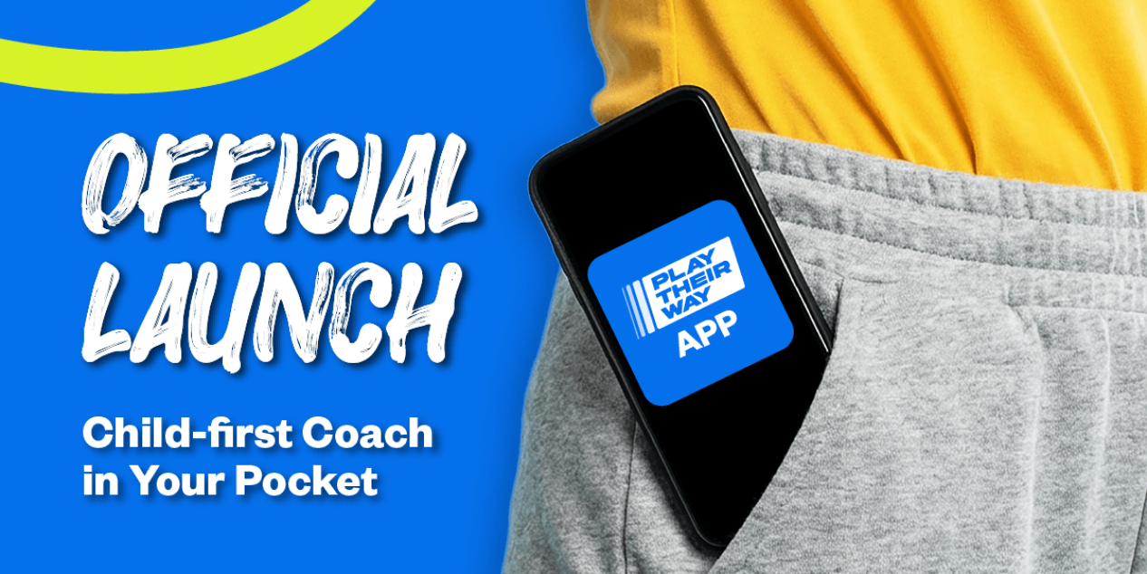 A mobile phone displaying the Play Their Way app is shown poking out of a pocket on a coach's tracksuit pants. Overlaid text reads 'Official launch - child-first coach in your pocket'.